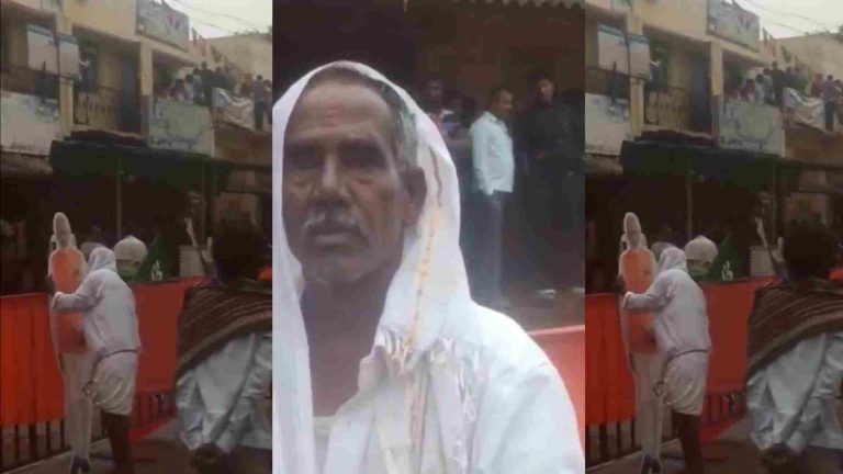 A man wipes PM Narendra Modi cut out standing beside road A man wipes PM Narendra Modi cut out standing beside road