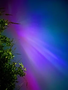 solar storm hits Earth, sky including northern lights sprinkles beautiful colors.